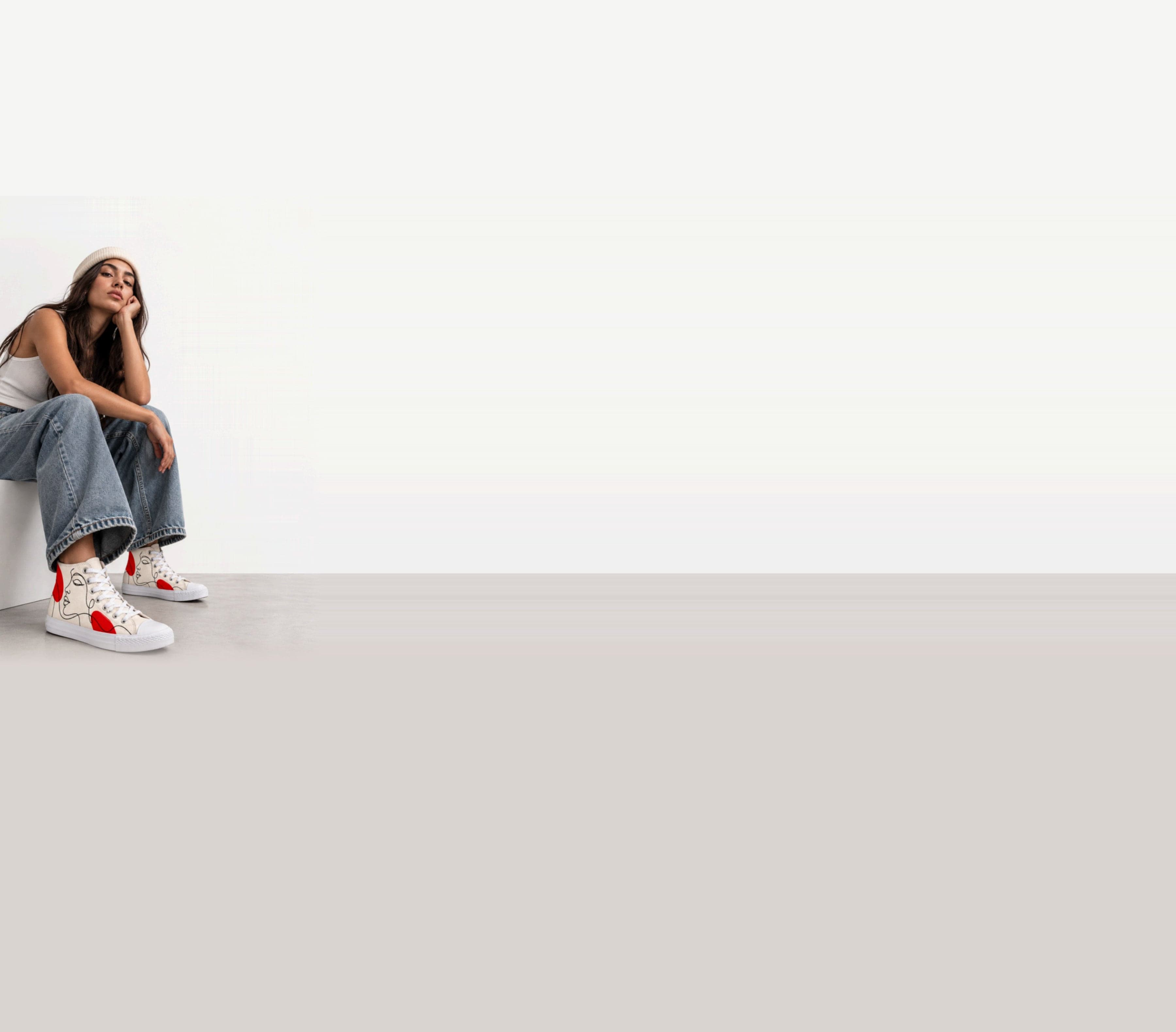Model sitting on a white block, wearing hand-painted PIMP IT high-top sneakers